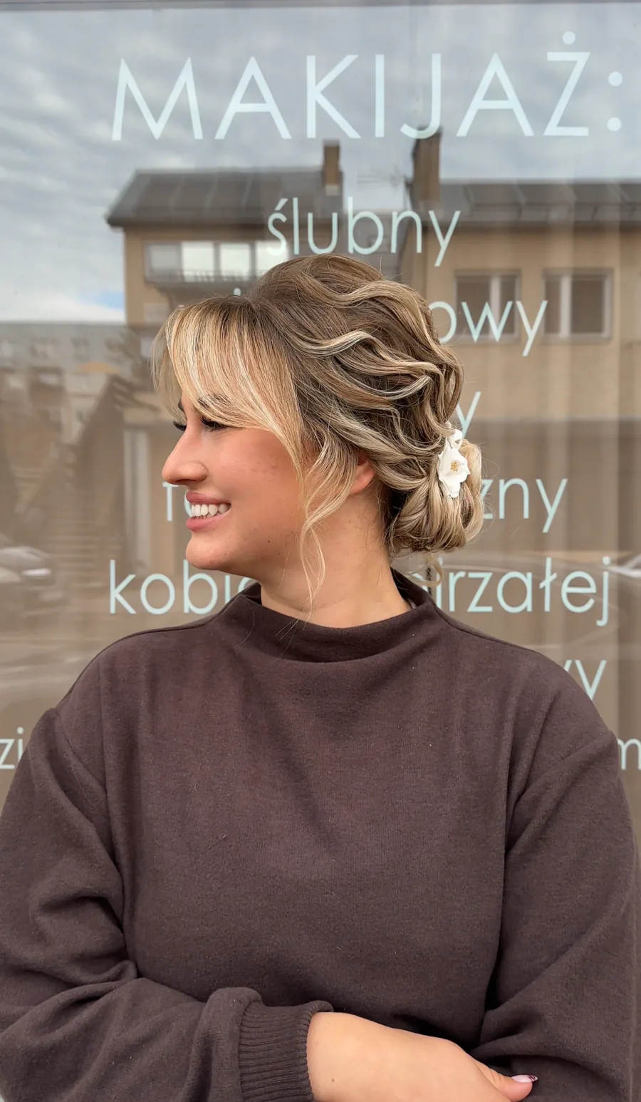 Uśmiechnięta klientka z jasnym upięciem i kwiatową ozdobą.